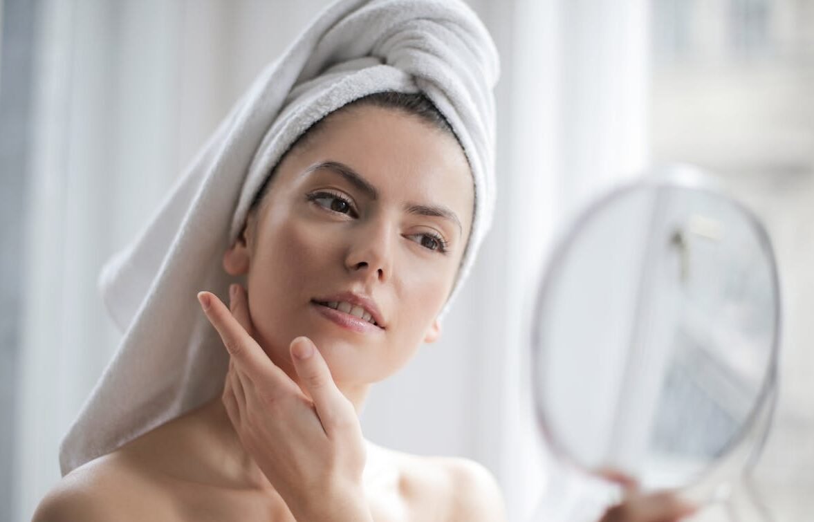 Selective Focus Portrait Photo of Woman With a Towel on Head Looking in the Mirror